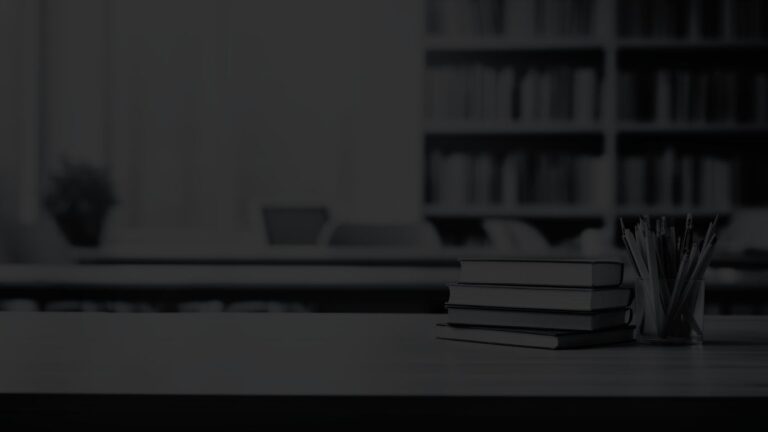 Close view of stacked books and a pencil holder in a group workspace