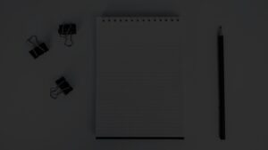 Overhead view of a graph notebook, binder clips, and a pencil