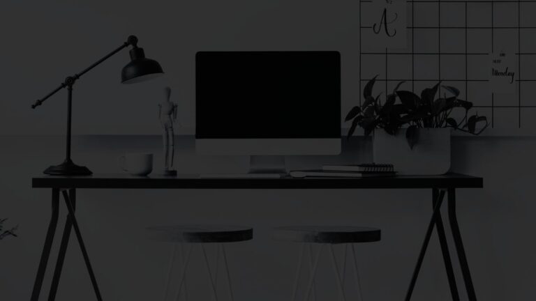 Detailed view of a home office setup with a large monitor, desk, and two stools