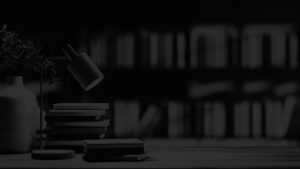 Desk lamp and stacked books in focus against a softly blurred bookshelf