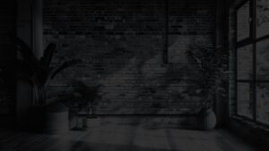 Minimalist office space featuring a modern brick wall and several large potted plants.