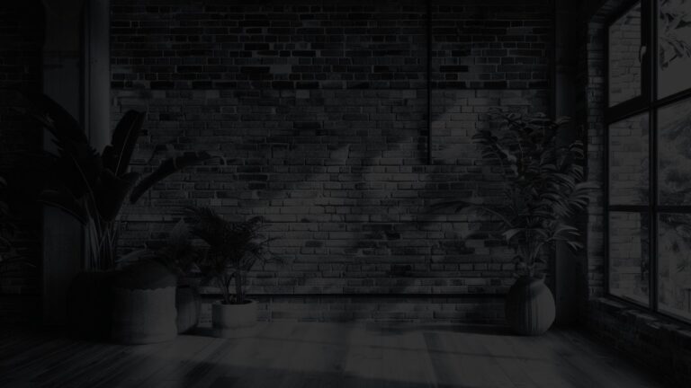 Minimalist office space featuring a modern brick wall and several large potted plants.