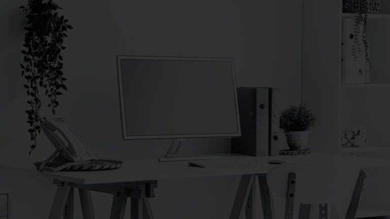 Angled view of personal office space, with a computer, standard phone, and house plants