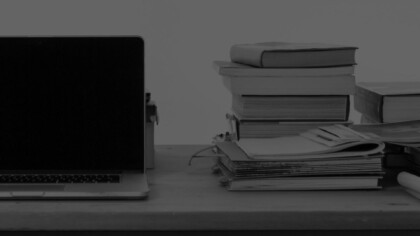 a laptop and a stack of textbooks on a desk