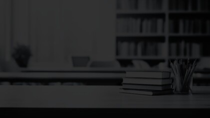 Close view of stacked books and a pencil holder in a group workspace