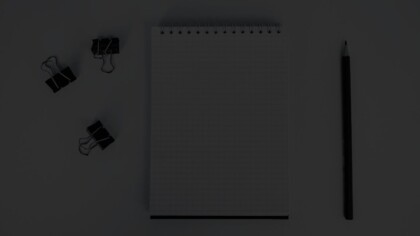 Overhead view of a graph notebook, binder clips, and a pencil
