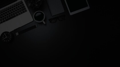 Neatly organized flat lay featuring an open laptop, iPad, eye glasses, coffee mug, pencils, and plant