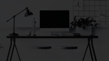 Detailed view of a home office setup with a large monitor, desk, and two stools