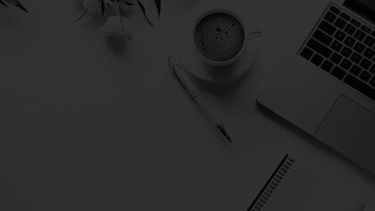 Overhead view of a workspace with a laptop, notepad, and cup and saucer