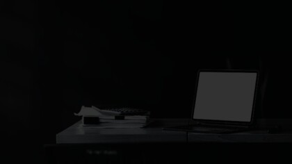 Desk corner featuring an open laptop and stacked documents