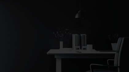 Simple desk in a dimly lit room with file folders, plants, and modern décor