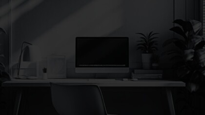 Large desktop computer, table lamp, and small house plant on simple wooden desk
