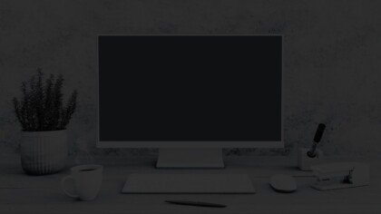 Simple desk set up featuring a monitor, keyboard, coffee, and various office supplies