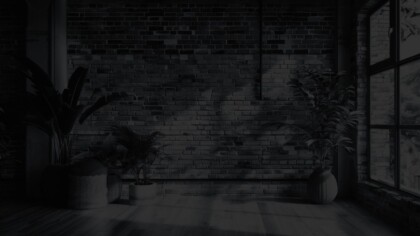 Minimalist office space featuring a modern brick wall and several large potted plants.