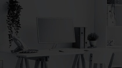 Angled view of personal office space, with a computer, standard phone, and house plants